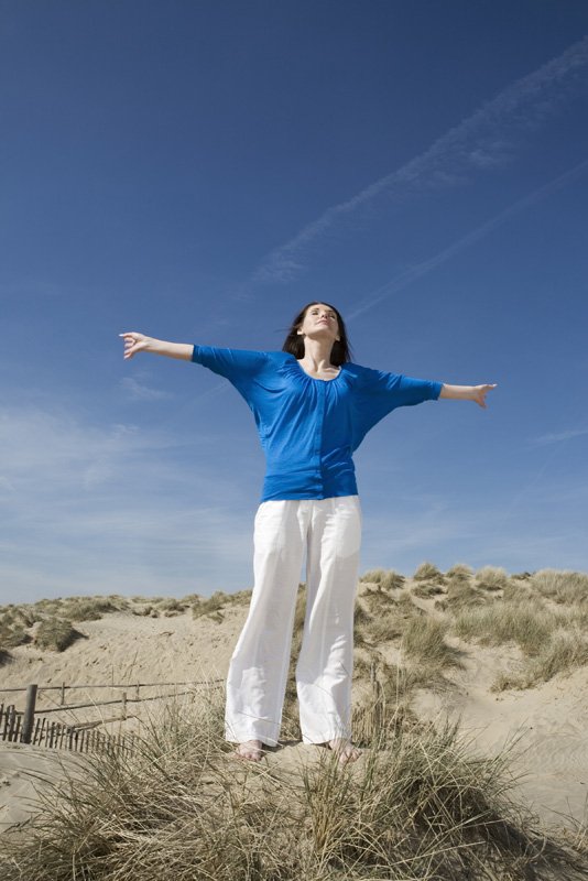 Mid adult woman standing with her arms open on the beach